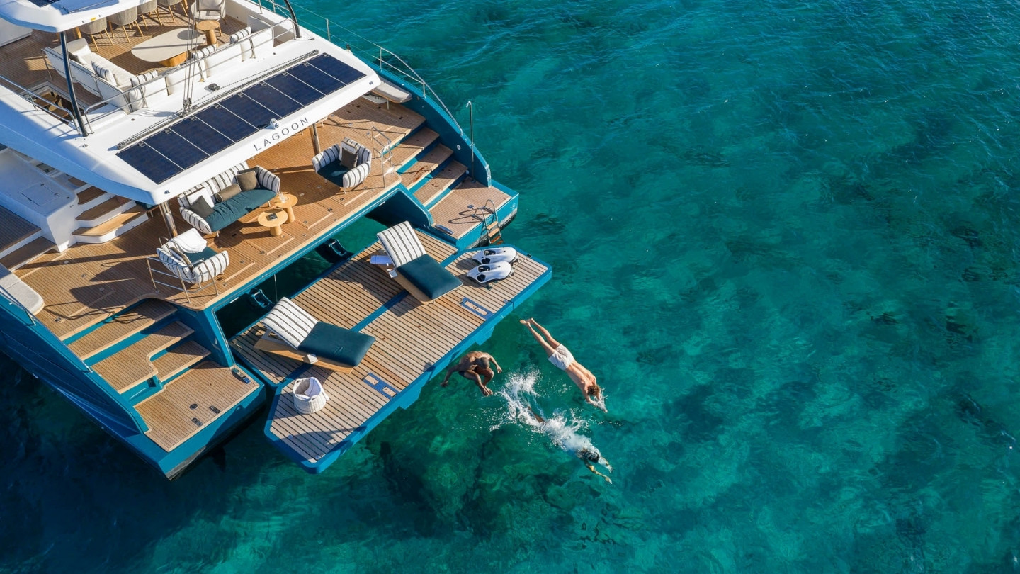 Aerial view of the Lagoon EIGHTY 2 catamaran with a swimmer entering the water from the swim platform